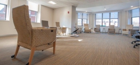 o	A Group Room at the Alexis Joy Center with comfortable chairs and tables in a U shape along the wall.
