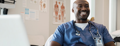 image of a nurse sitting in front of a computer smiling
