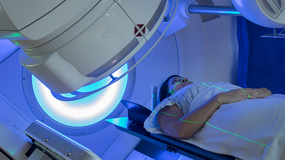 A patient laying down, wearing a patient gown, and waiting to be scanned by the imaging machine.