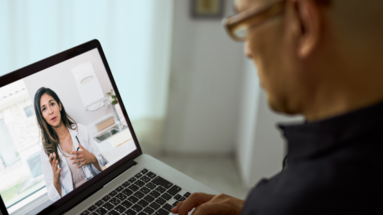 A man watching video on his laptop while a female doctor explains the risk factors for colorectal cancer.