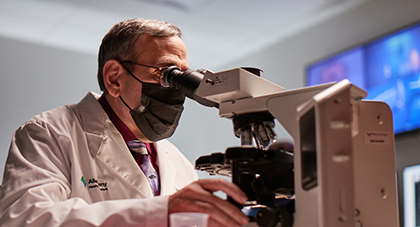 An AHN researcher looking at samples through a microscope.