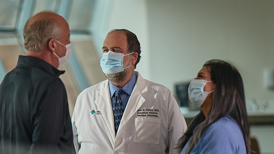 A group of oncologists wearing masks discussing a patient.