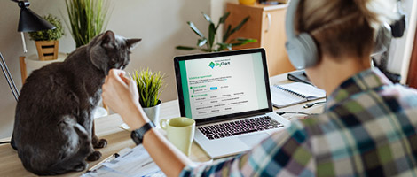 A man using the MyChart online scheduling tool on his laptop while petting his cat.