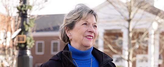 Woman smiling at the camera as her photo is taken on a bench outside